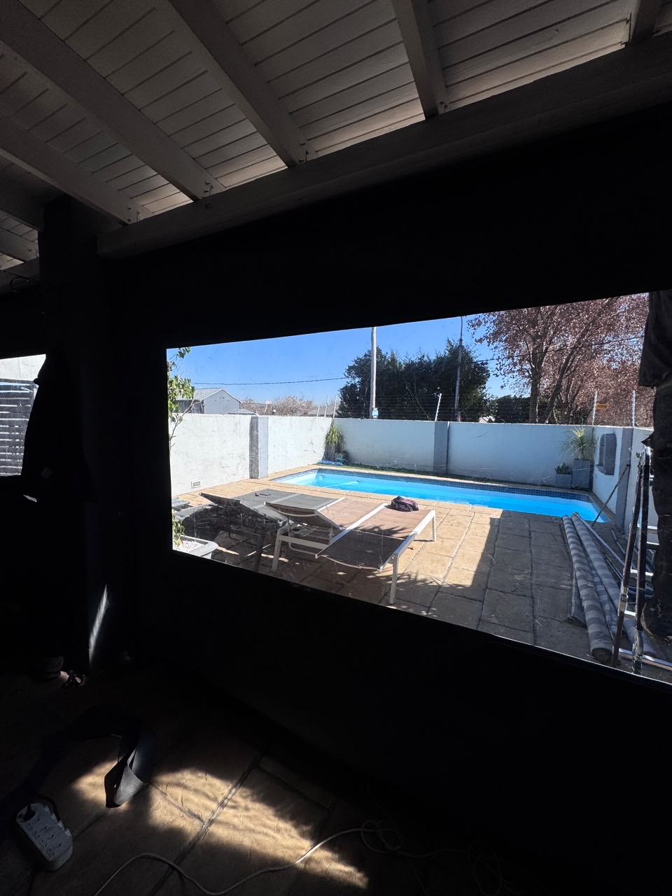 Pool view framed by a charcoal blind picture window