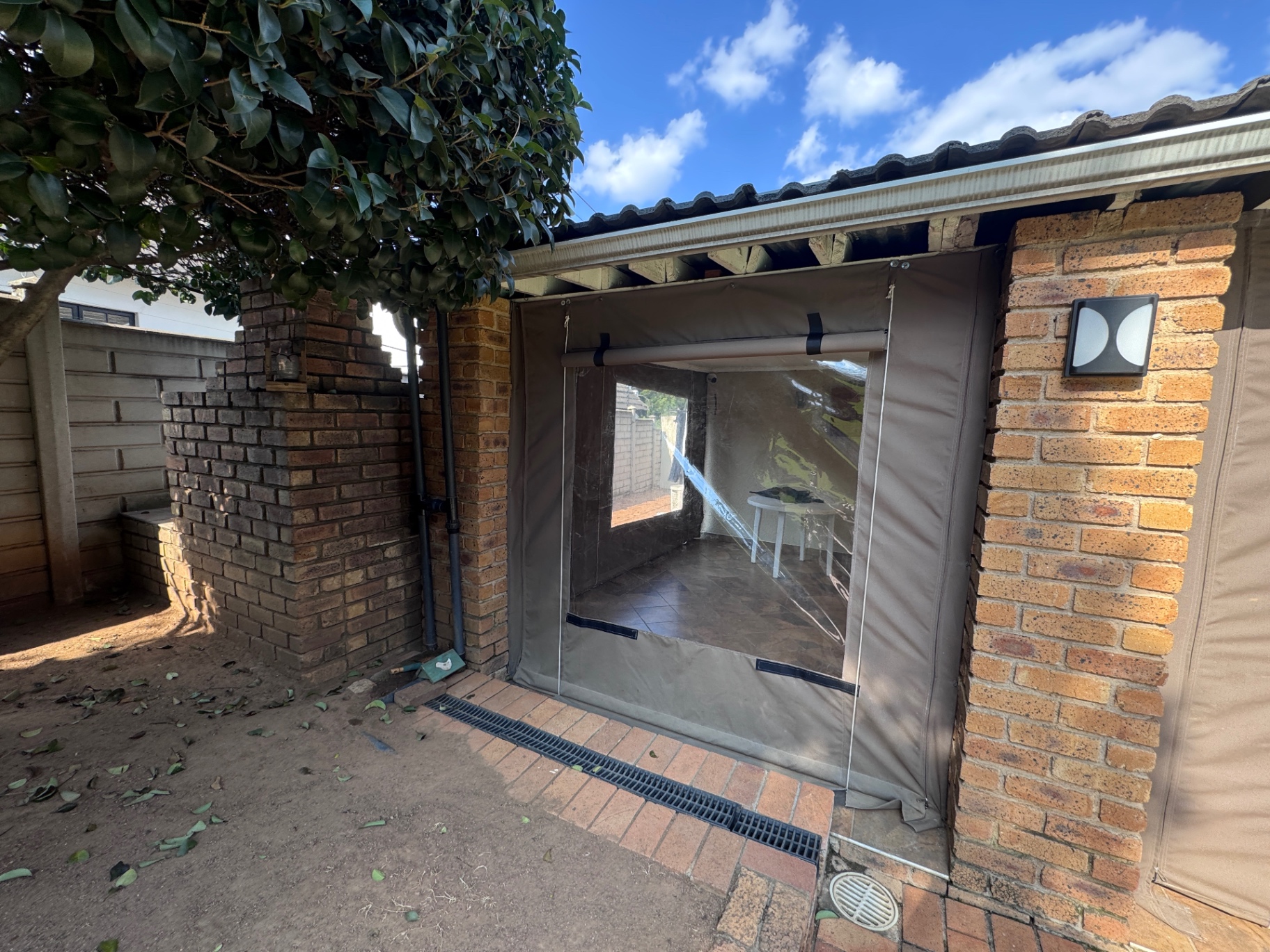 Brick patio enclosed with canvas roller blinds and a clear window